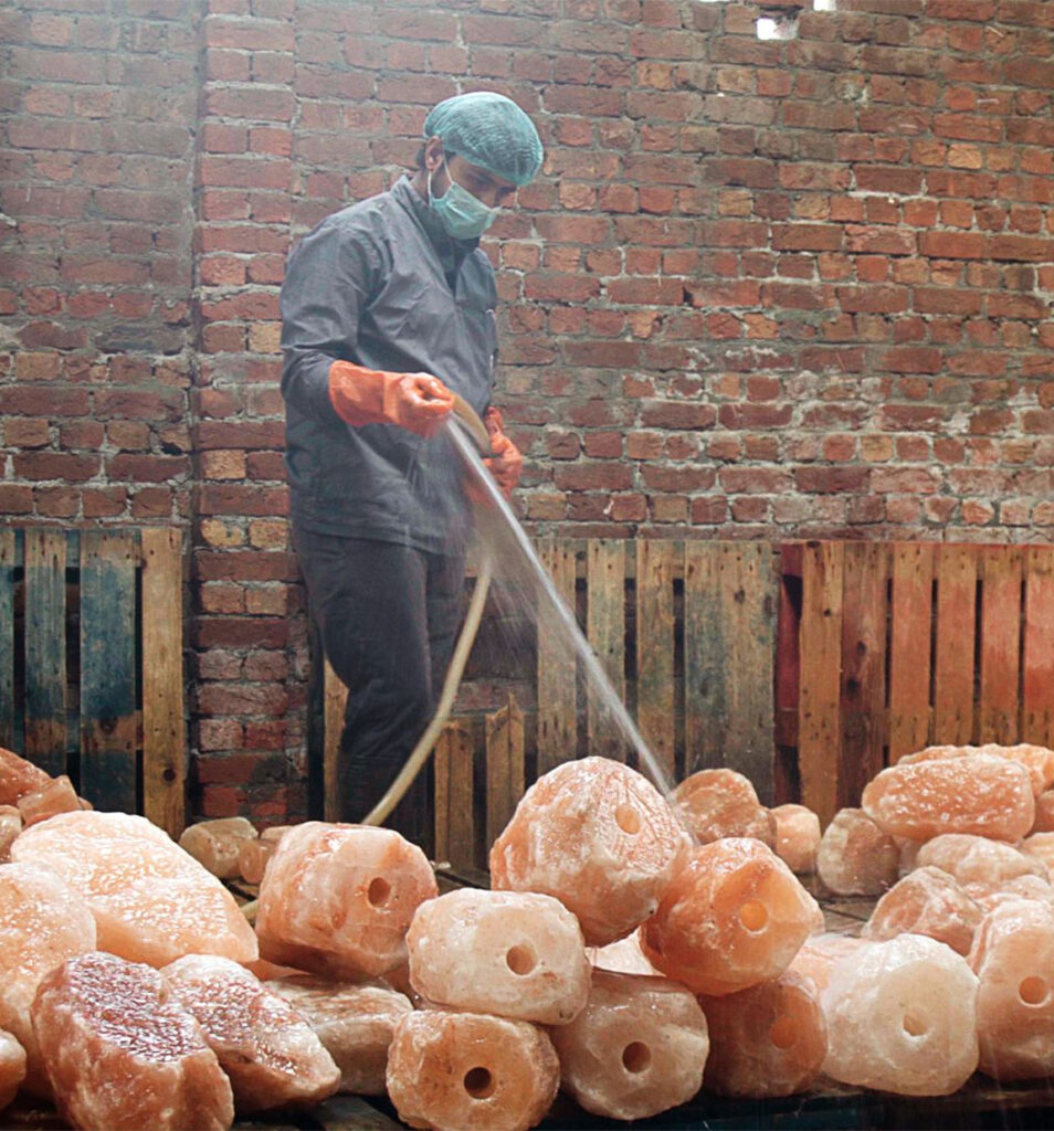 Worker washing Himalayan pink salt rocks in a salt processing plant